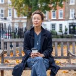 New Zealand travelling nurse on her break in London, sitting on a wooden bench in a traditional London garden square